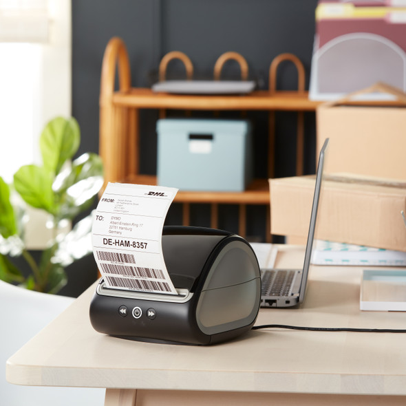Dymo LabelWriter printer on a home office desk with parcel and mailing supplies