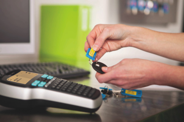 Person using a DYMO LabelManager 420P to create labelled key tags for organised key management
