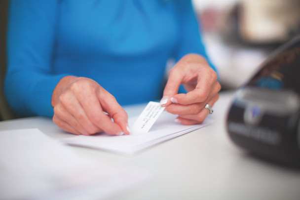 Hands applying a large shipping label to a parcel