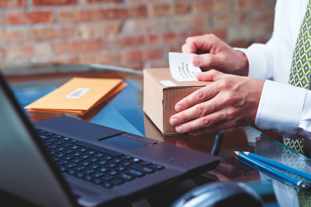 Hand placing a shipping label onto a blue parcel