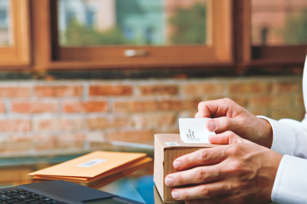 Shipping label being applied to a cardboard box at a packing bench