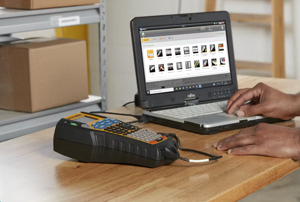 DYMO Rhino 6000 Plus industrial label maker connected to a laptop on a workbench, used for asset labelling and record keeping. | DymoOnline