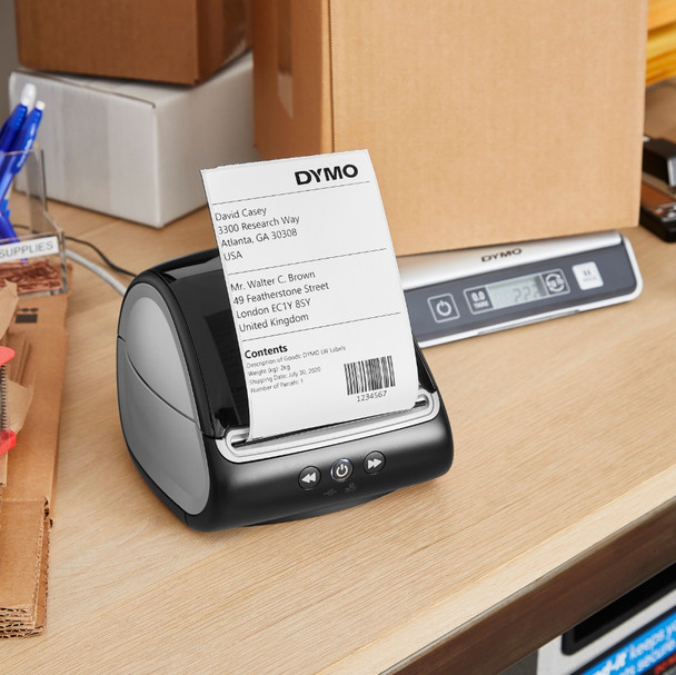 DYMO LabelWriter 5XL label printer on an office desk printing a shipping label with stationery in the background.