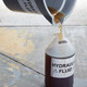 Hydraulic fluid being poured into a labelled container with DYMO durable identification and barcode label applied