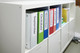 Colour coded lever arch files with spine labels in shelf storage