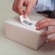 Hands applying a label to a small white parcel