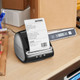DYMO LabelWriter 5XL label printer on an office desk printing a shipping label with stationery in the background.