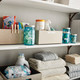 Organised household shelves with labelled containers and folded towels