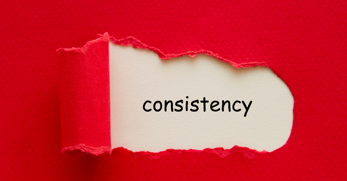 The word consistency revealed on torn paper, representing disciplined habits that build long-term business growth and momentum