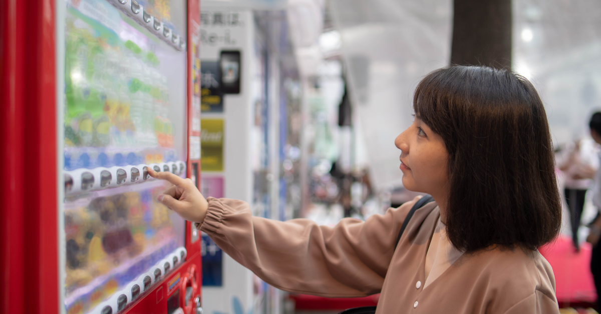 Person purchasing a snack from a vending machine, illustrating strong demand for quick snacks and drinks in a high-traffic location.