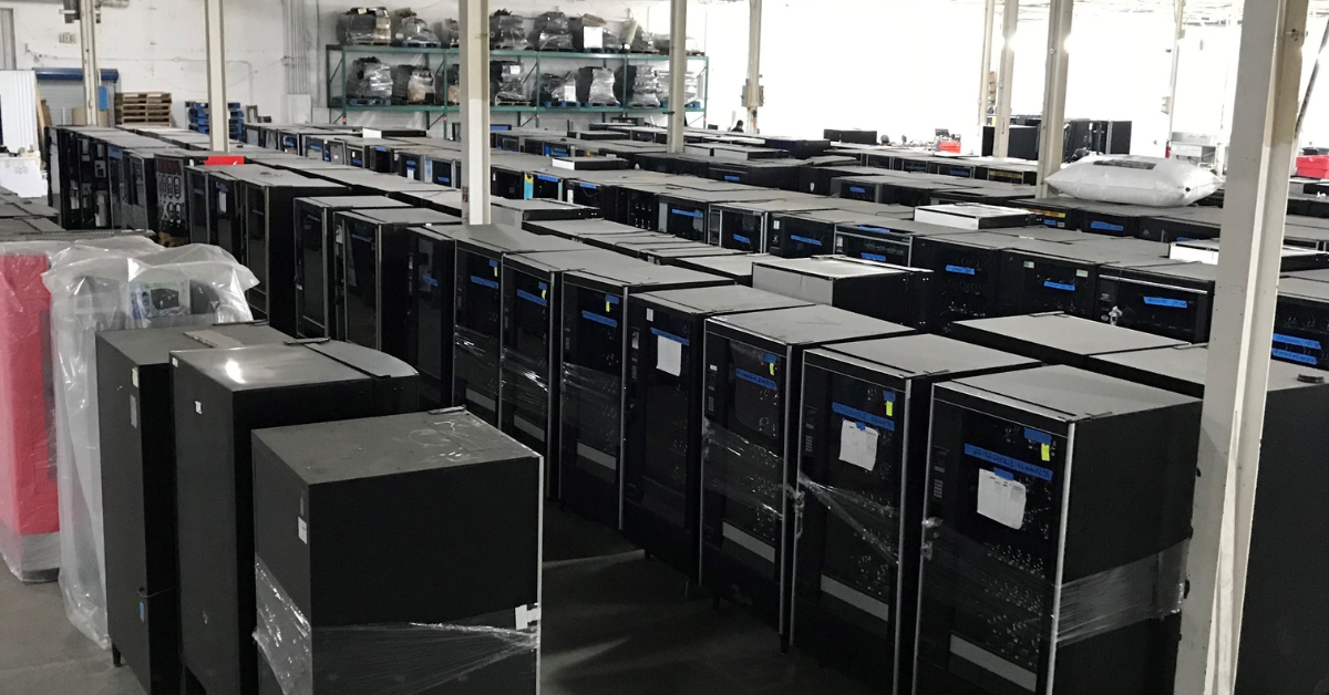 Warehouse with rows of used vending machines ready for inspection before purchase, illustrating the importance of evaluating equipment condition and serviceability.