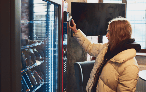 Person using a card reader on a vending machine, showing a convenient payment option at a workplace location.