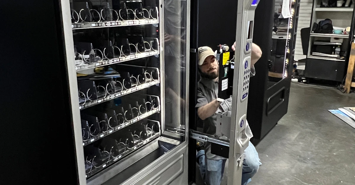 Technician inspecting and testing a vending machine to verify its condition before sale