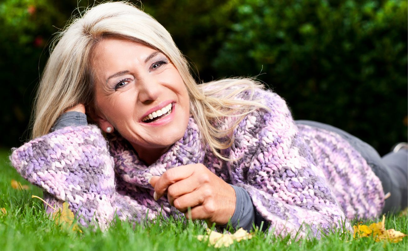 Mature woman happily laying in the grass enjoying the sunshine