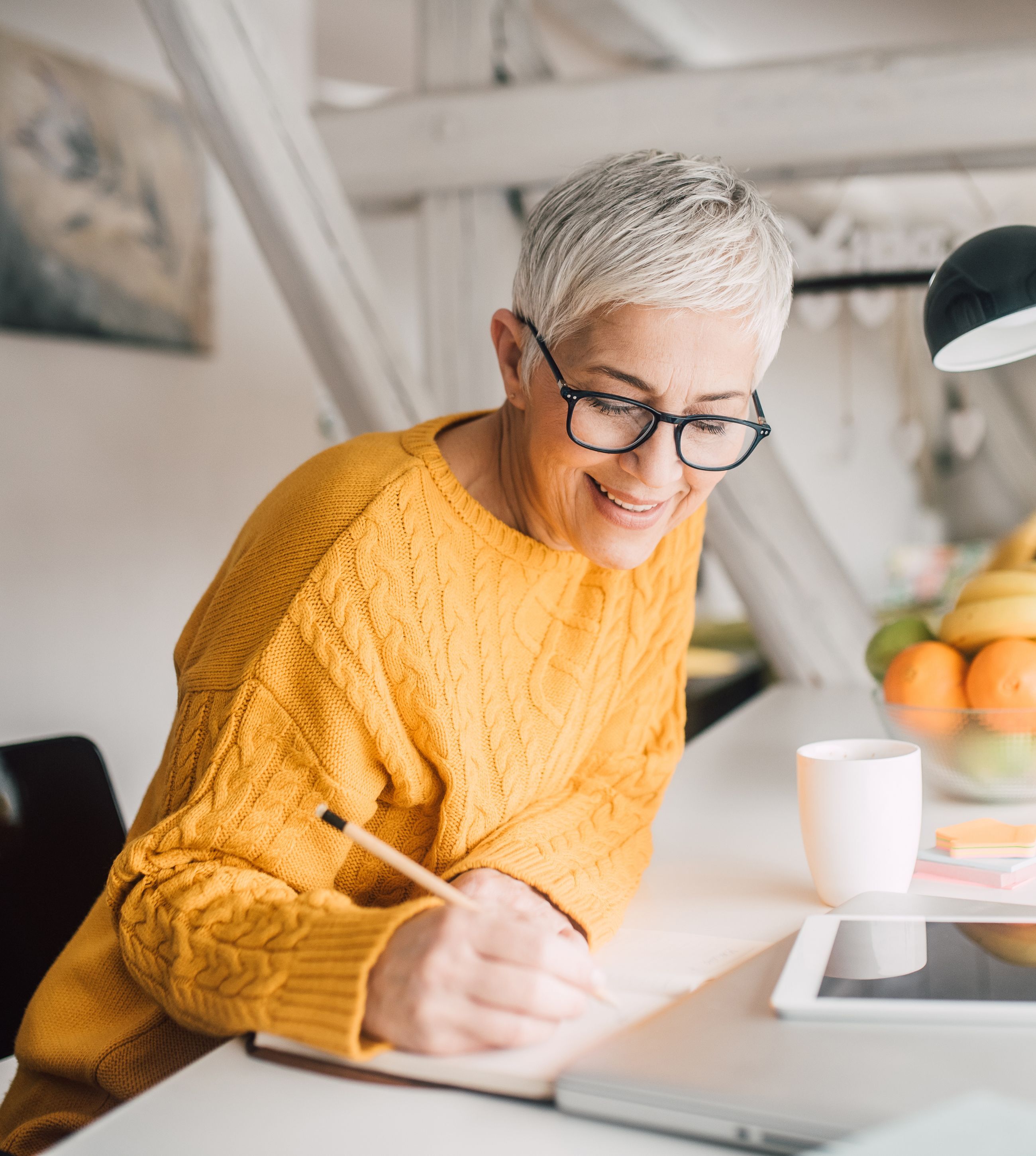 Mature woman in the kitchen writing in her journal