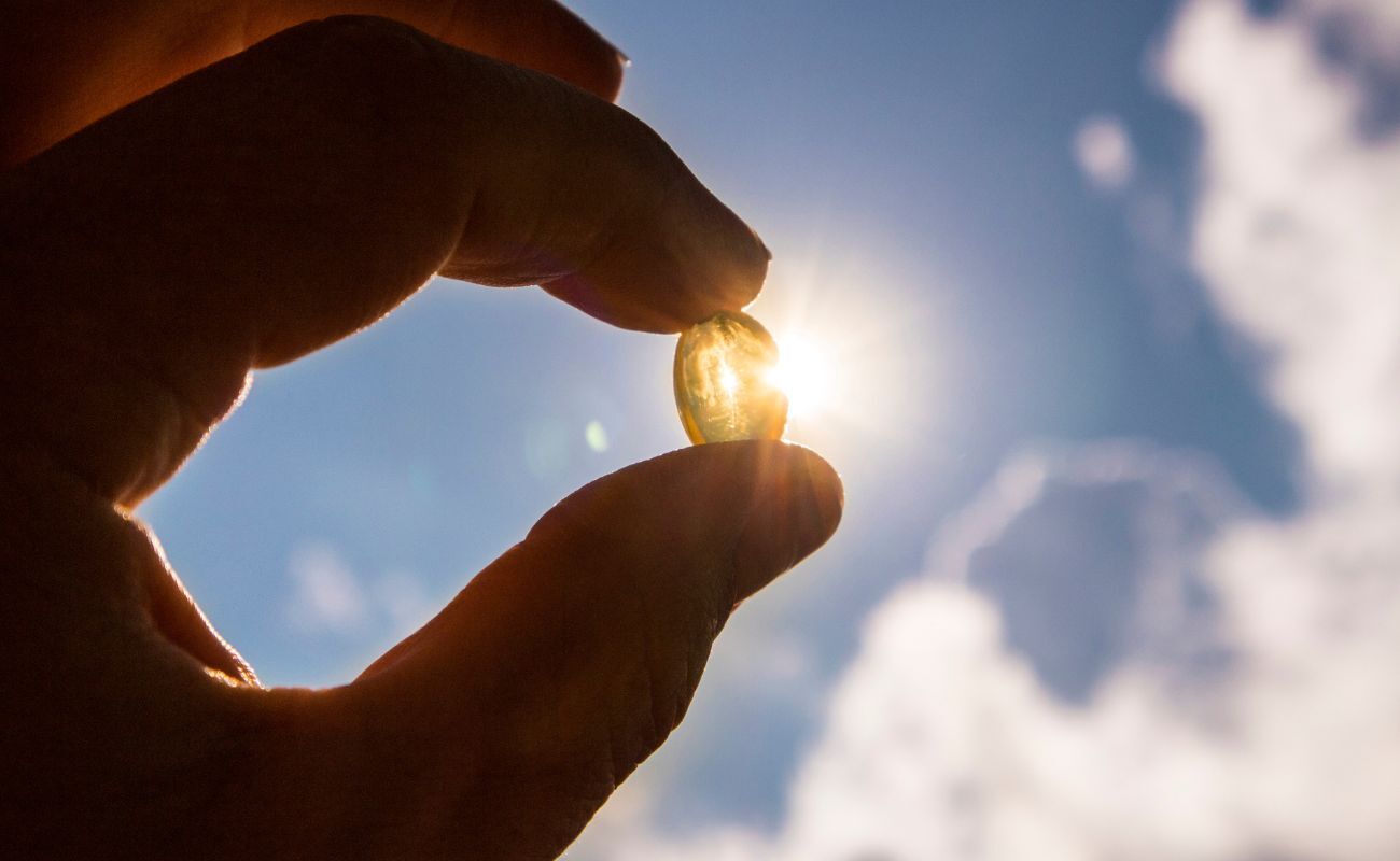 Photo of a vitamin D softgel being held up to the sunlight.