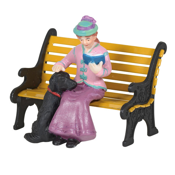 Seated lady pats her black lab dog's head, while reading her book. This general accessory is hand-crafted, hand-painted, porcelain. Bench sold separately.
