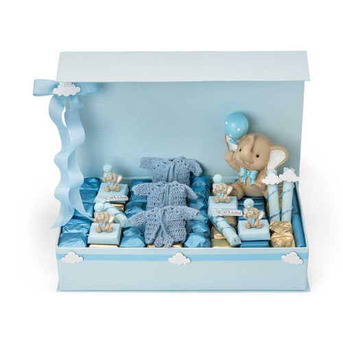 A light blue chocolate gift box featuring an elephant figurine holding a blue balloon, with four smaller elephant figurines attached to wrapped chocolates, two crochet jackets, and an assortment of chocolates in blue and gold foil wrappers.