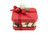 A festive red chocolate gift box with a matching red lid and base, filled with assorted chocolates in holiday-themed wrappings, tied with an elegant ribbon, and decorated with sparkling ornaments and frosted greenery.