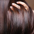 A closeup image of fingers being run through healhy looking, shiny hair.