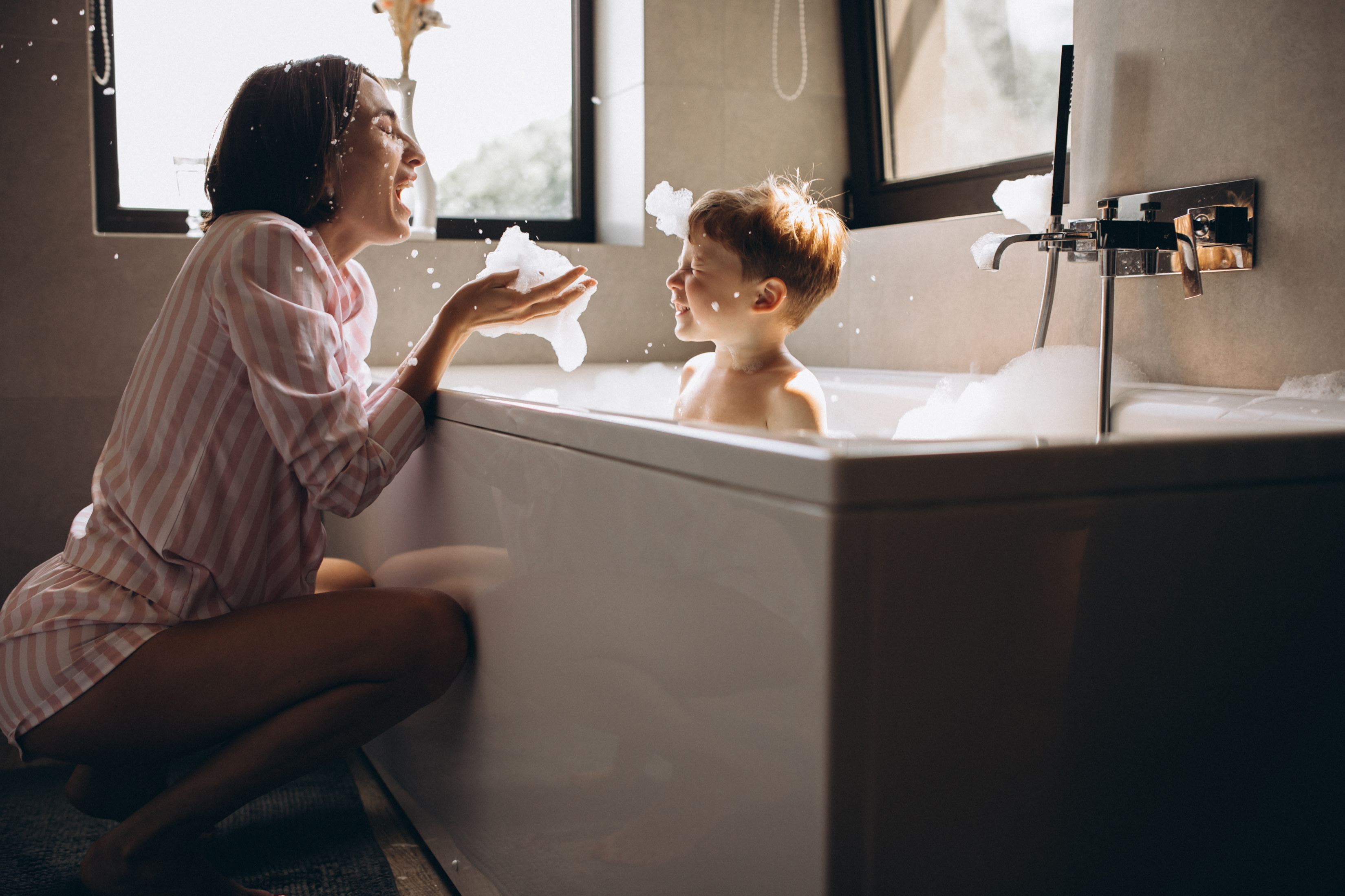 Mother is having fun with young son in the bath