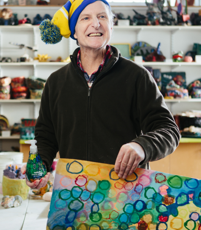 Person holding soap bottle with painting in other hand