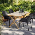 Cane-line four Breeze stackable chairs in Black around a wooden table.