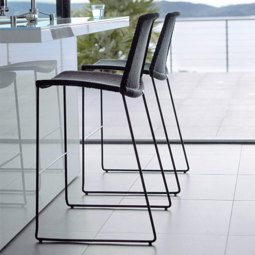 Cane-line Breeze bar chairs in black in front of a bar.