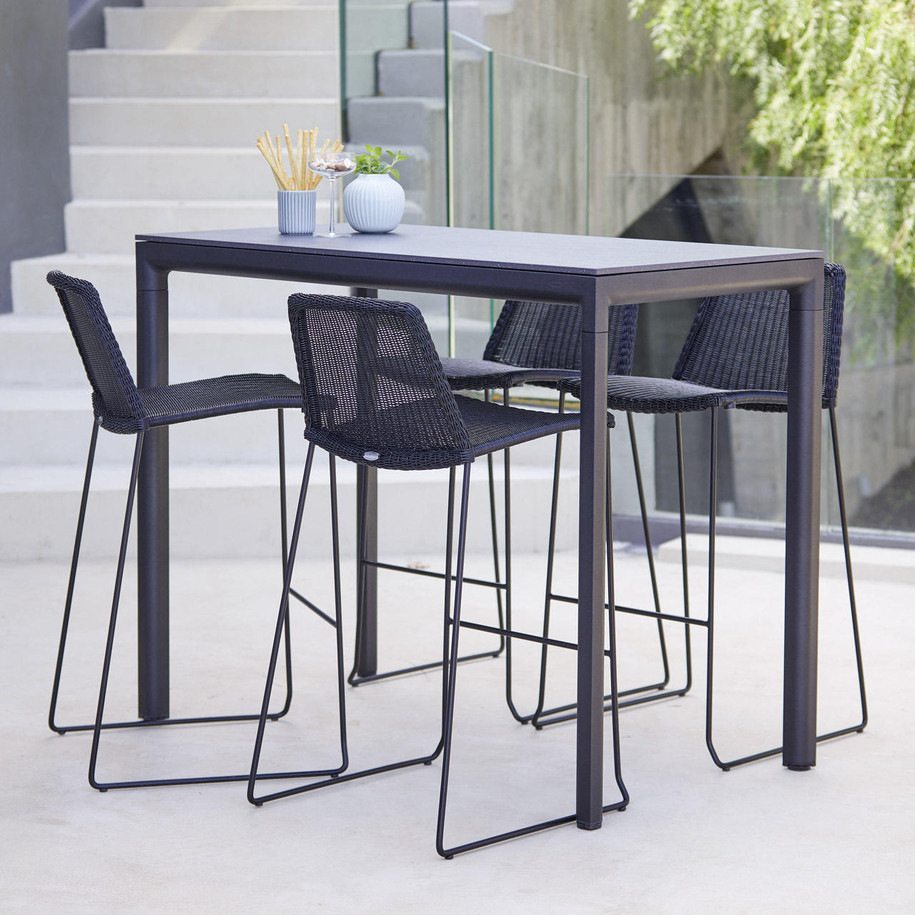 Cane-line Breeze four bar chairs in black in front of table.