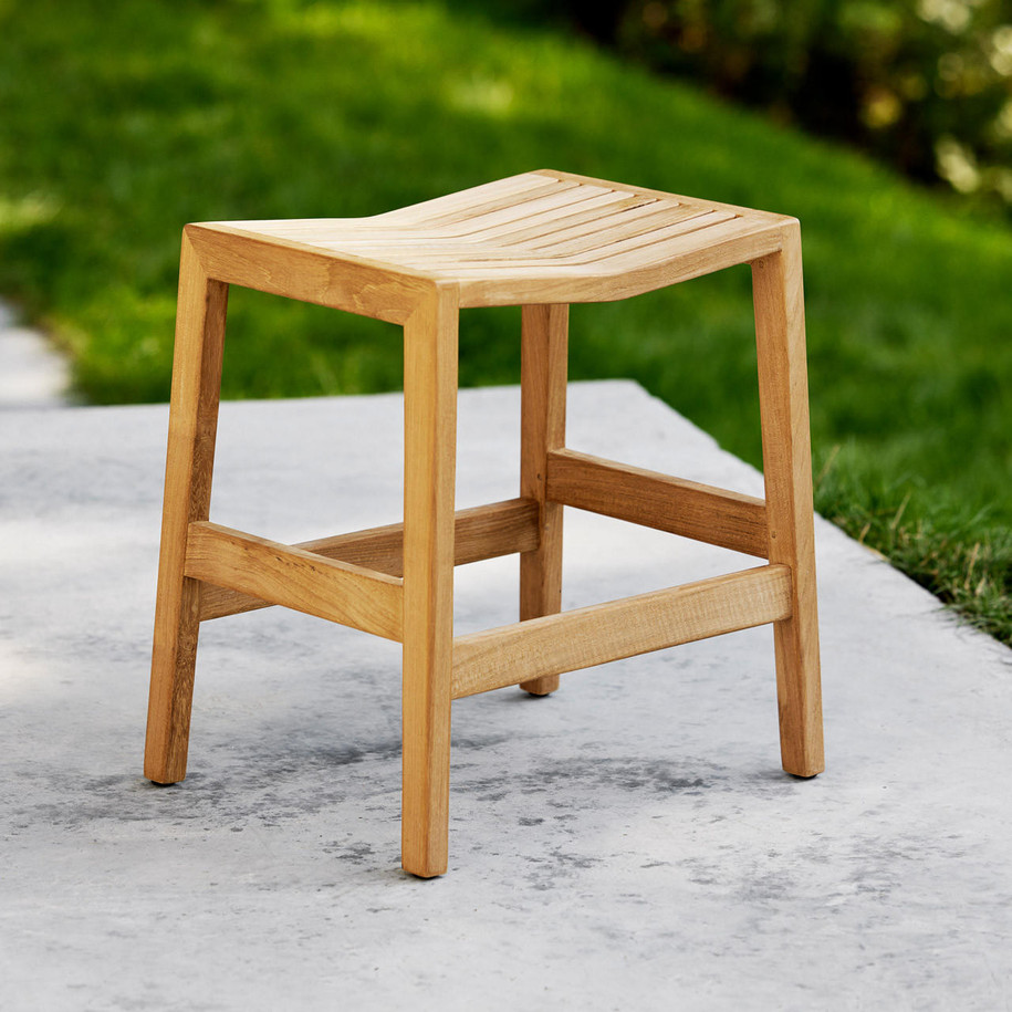 Cane-line Flip stool outside by grass.