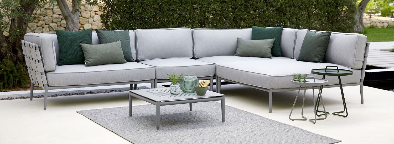 Cane-line outdoor furniture in a garden setting, Conic range with on-the-move tables