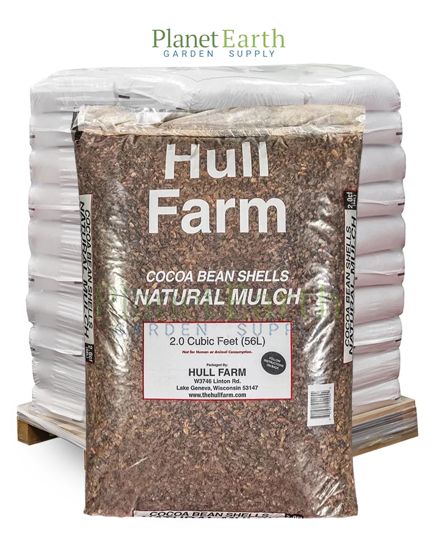 Pallet of stacked white Hull Farm cocoa shell mulch bags with one featured bag in front.