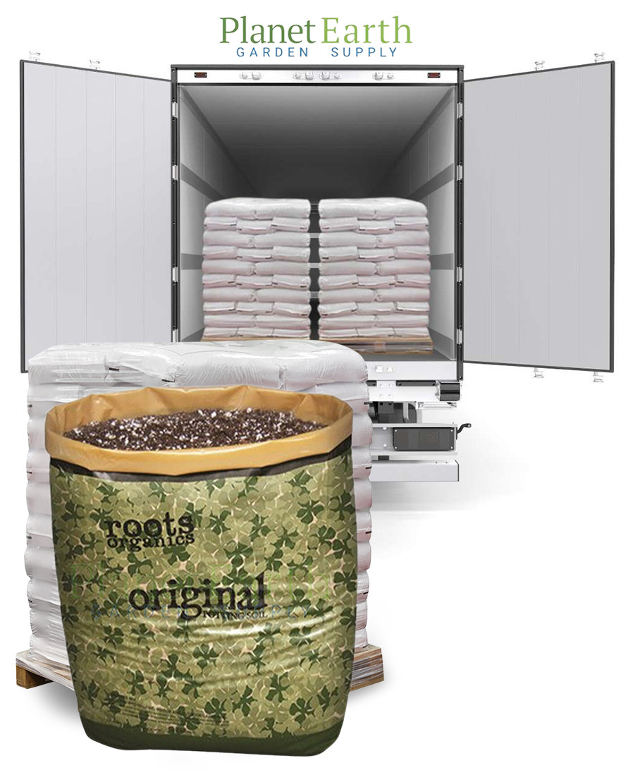 A pallet of Roots Organics potting soil bags, with a semi-truck loaded with pallets in the background.