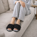 Woman relaxing in black curly plush open-toe house slippers