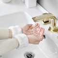 White plush spa wristbands worn while washing hands at a sink
