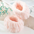 Pair of blush plush spa wristbands arranged on a light surface