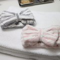 Gray-and-white and pink-and-white striped bow spa headbands on a towel