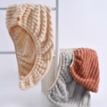 Beige chenille hair towel cap hanging beside gray and brick red caps