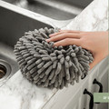 Hand resting on a gray round hand towel beside a sink
