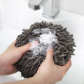 Hands holding a gray round hand towel covered with soap lather