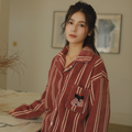 Woman wearing relaxed rust red plush pajama top with contrast stripes and chest pocket