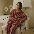 Woman seated in rust red striped plush fleece pajama set for cozy cold-weather lounging