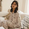 Woman seated on a sofa wearing the Ink Garden viscose floral pajama set