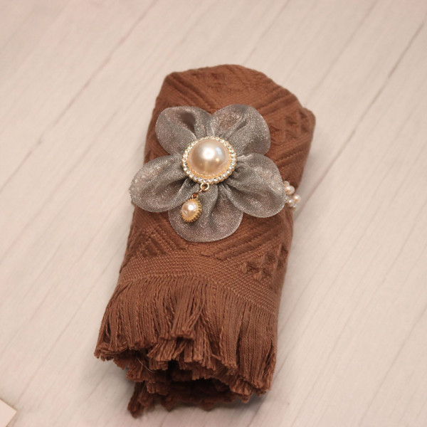 Brown fringed towel with a gray flower hair tie