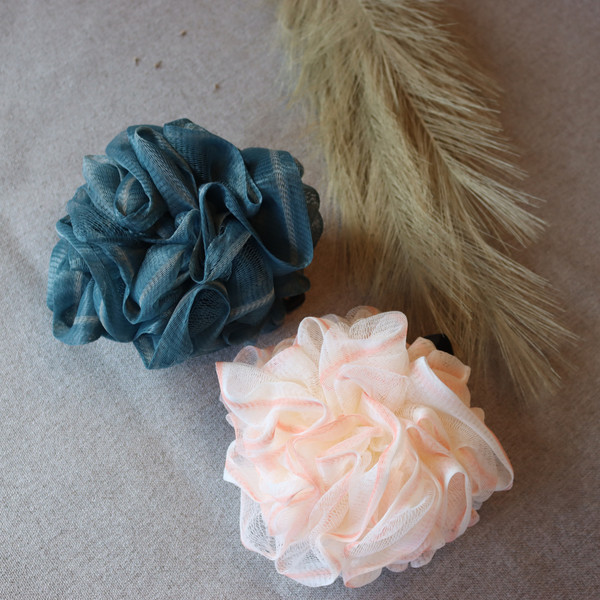 Navy blue and pink mesh bath poufs on a neutral surface