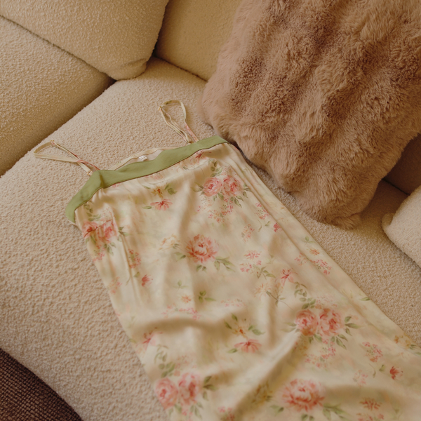 Botanical floral slip nightdress draped on a neutral upholstered chair