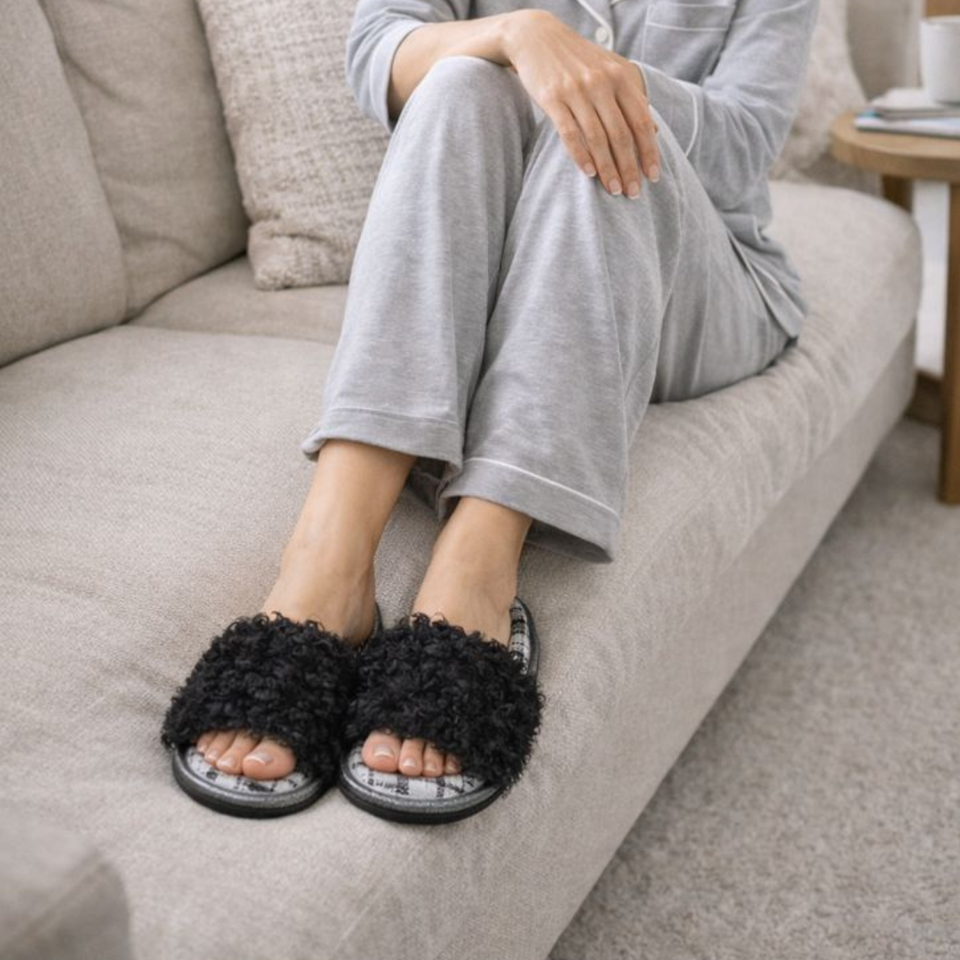 Woman relaxing in black curly plush open-toe house slippers