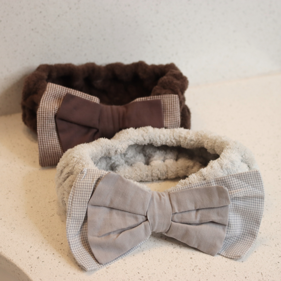 Gray and brown textured plush bow spa headbands on a neutral surface