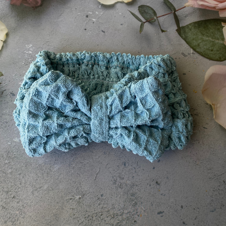 Blue waffle-texture bow spa headband on a floral backdrop
