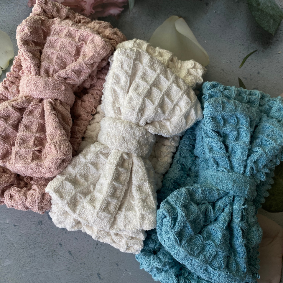 Close-up of beige, blue, and pink waffle-texture bow spa headbands
